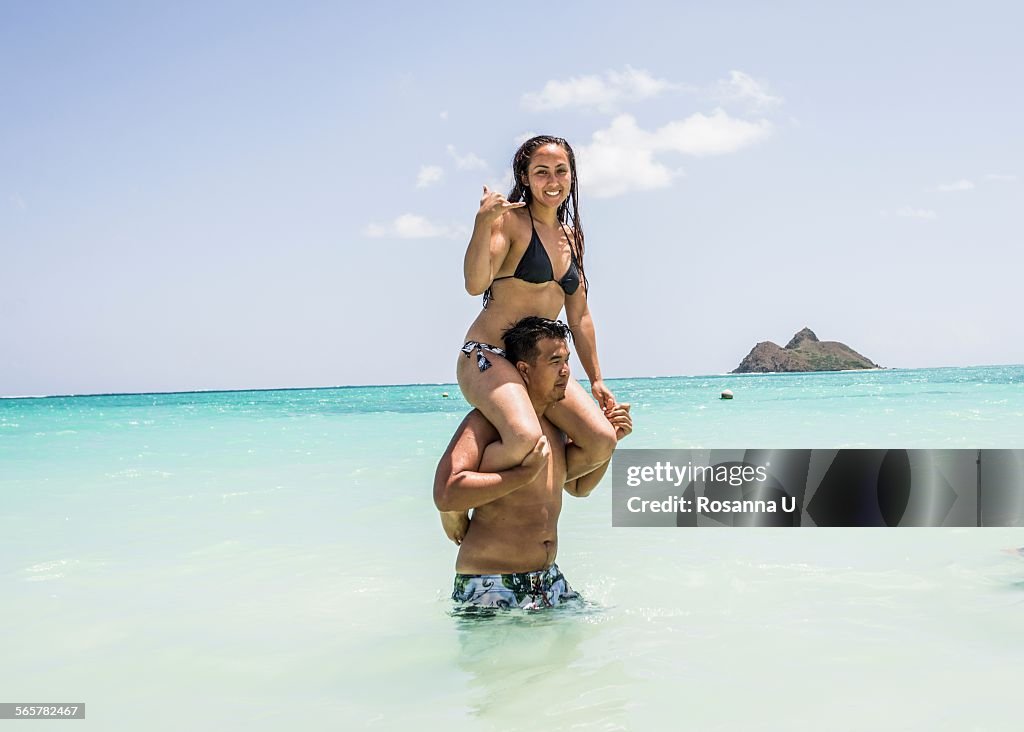 Portrait of young woman getting shoulder ride from boyfriend in sea at Lanikai Beach, Oahu, Hawaii, USA