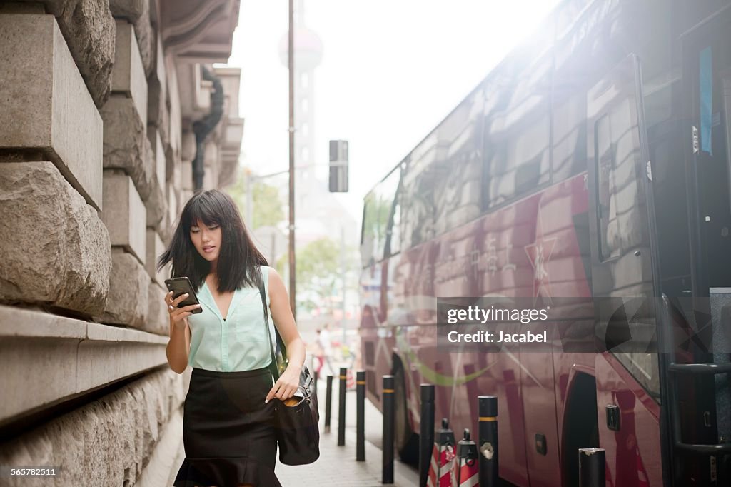 Young businesswoman, using smartphone, outdoors, Shanghai, China