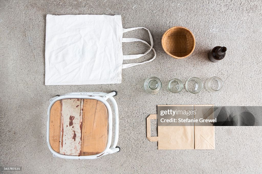 Overhead still life of stool, reusable shopping bag and recyclable paper and bottles