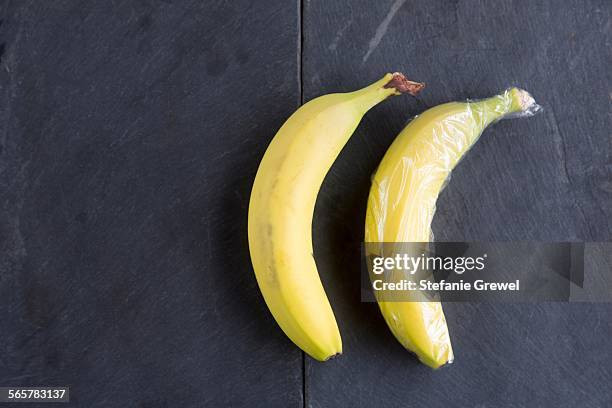 still life of two bananas - one wrapped in plastic wrap - polythene stock pictures, royalty-free photos & images