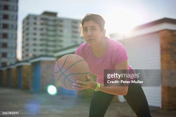 Mature woman practicing basketball at dusk