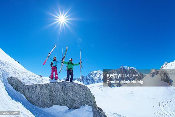 male and female skiers holding up skis on mont blanc massif, graian alps, france - mont blanc massif stock-fotos und bilder