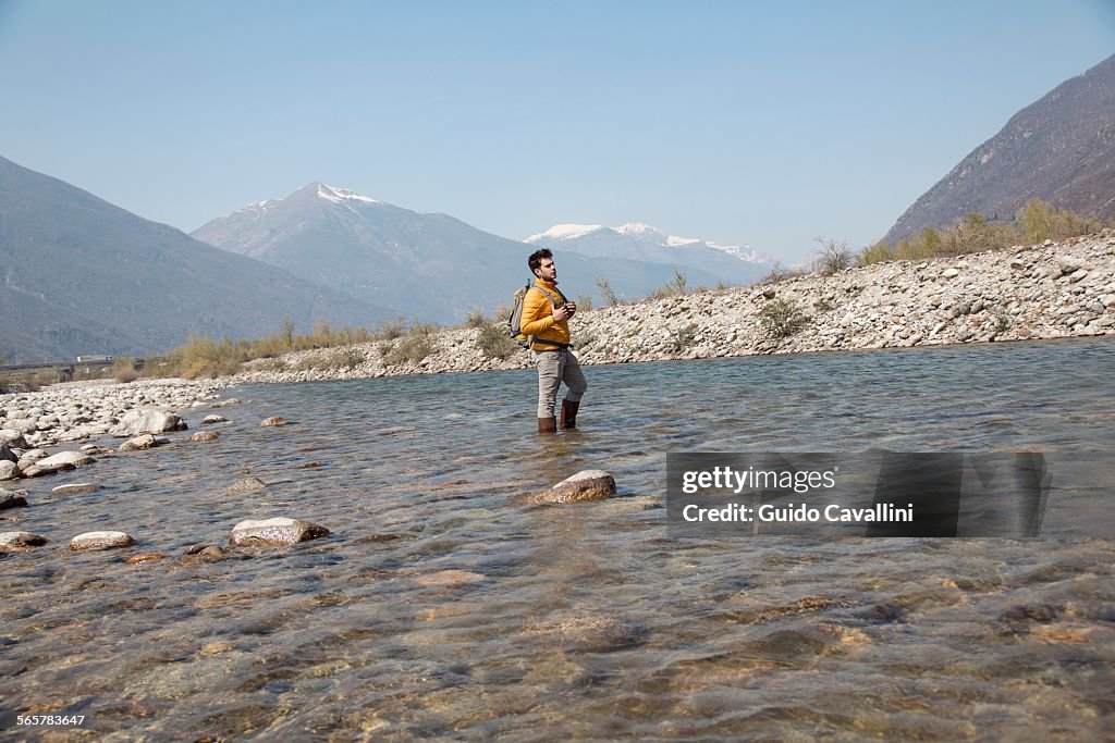 Young male hiker looking out from Toce river, Vogogna, Verbania, Piemonte, Italy