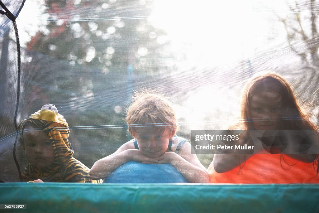 Young children looking out from garden trampoline