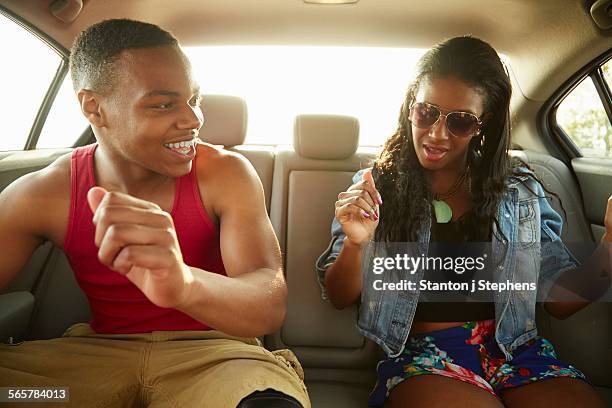 Young couple in back seat of car showing off dance moves