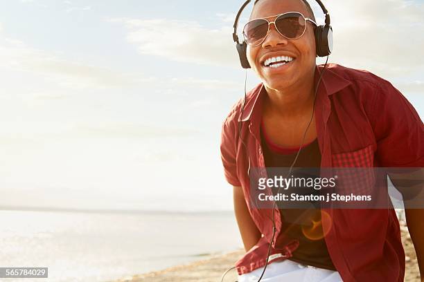 young man wearing headphones and sunglasses, smiling looking at camera - beach music stock pictures, royalty-free photos & images
