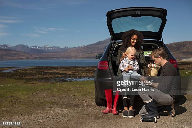 parents helping son change shoes, loch eishort, isle of skye, hebrides, scotland - auto familie stock pictures, royalty-free photos & images
