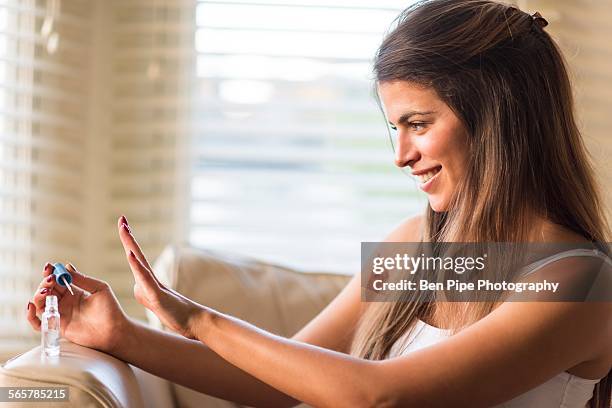 young woman looking at newly painted nails - home manicure stock pictures, royalty-free photos & images