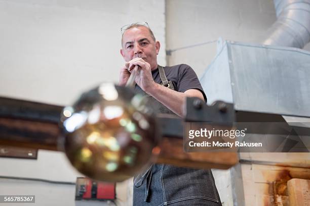 glassblower blowing hot glass - glass blowing stock pictures, royalty-free photos & images