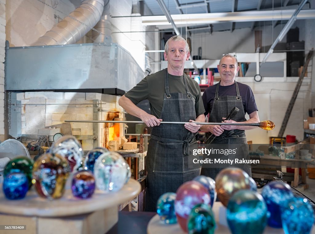 Artisan glassblowers in workshop with furnace and finished glassware