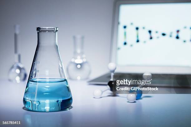 chemistry research. erlenmeyer flask containing colored liquid, a ball-and-stick molecular model and laptop computer - beuta foto e immagini stock