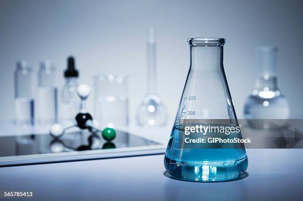 chemistry research. erlenmeyer flask containing colored liquid and a digital tablet with a ball-and-stick molecular model on its screen - flask stock pictures, royalty-free photos & images