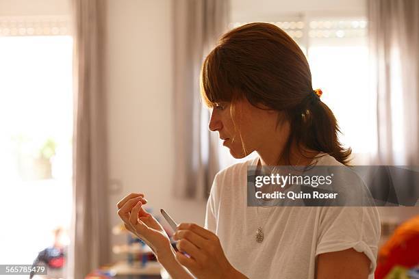 mid adult woman at home using nail file - nagelfeile stock-fotos und bilder