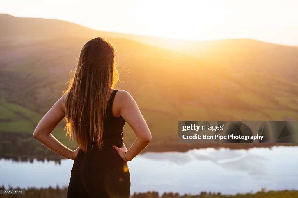 Rear view of young woman looking out over Talybont Reservoir in Glyn Collwn valley, Brecon Beacons, Powys, Wales