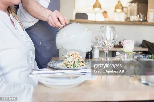 midsection of waiter lifting cloche from dish for customer in restaurant - yoghurt lid stock pictures, royalty-free photos & images