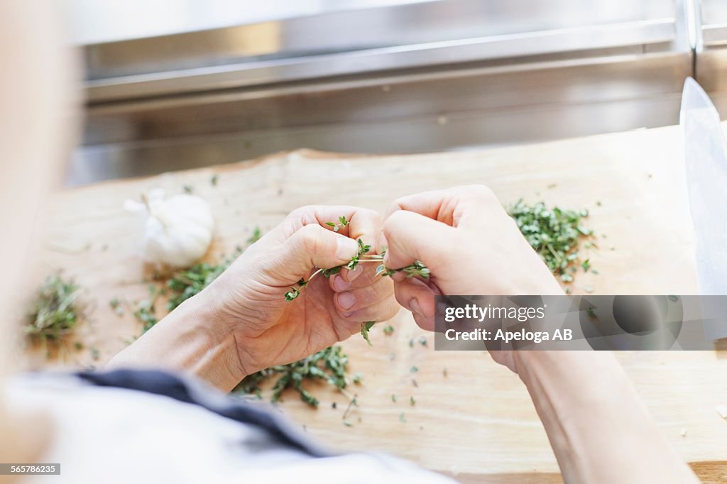 Cropped image of chef cleaning lemon thyme in kitchen