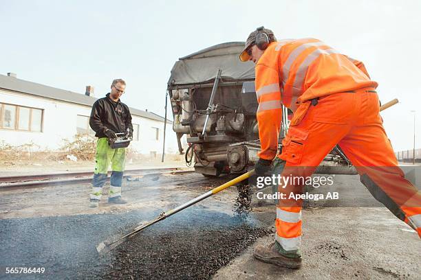 manual workers paving at road construction site - tejer stock-fotos und bilder