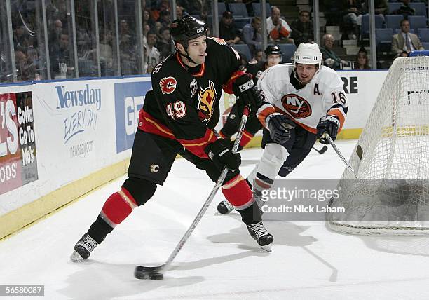 Richie Regehr of the Calgary Flames clears the puck under pressure from Mike York of the New York Islanders on January 12, 2006 at Nassau Coliseum in...