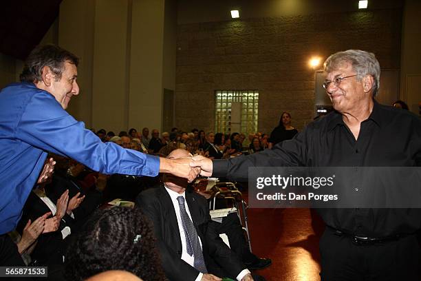 Israeli musician and composer Yoni Rechter shakes hands with American conductor Stanley Sperber at the annual meeting of the Board of Governors of...