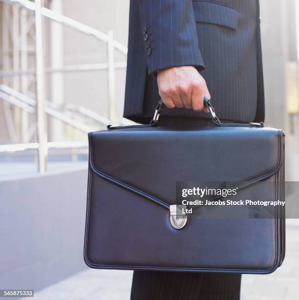 hispanic businessman carrying briefcase - aktentasche stock-fotos und bilder