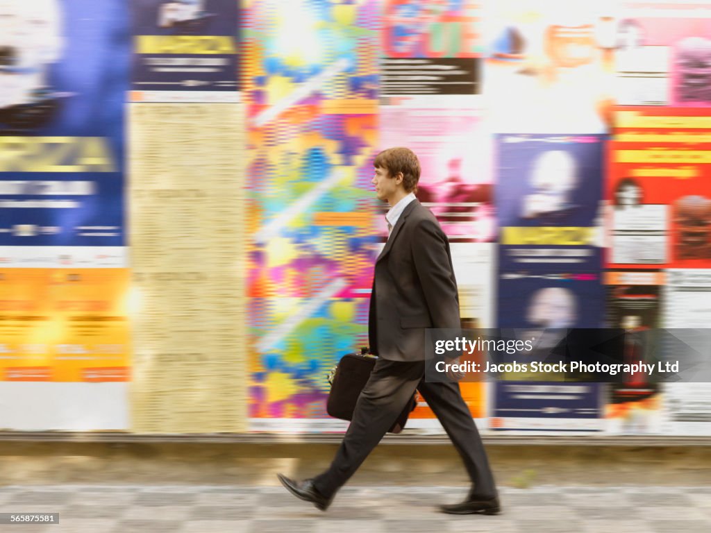 Blurred view of Caucasian businessman walking on city sidewalk
