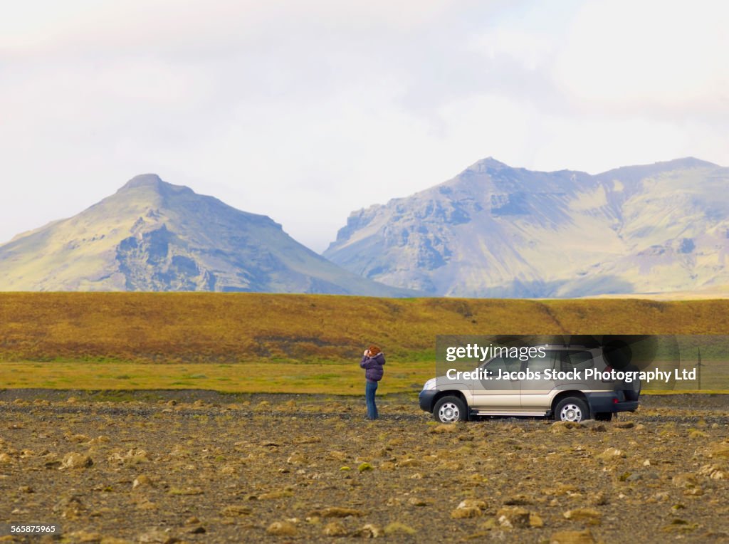 Caucasian woman admiring mountains from remote road, Vik, Southland, Iceland