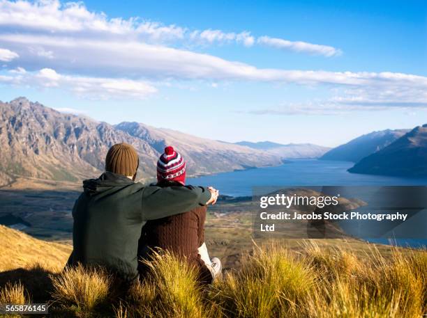 hikers admiring scenic view from hilltop, queenstown, south island, new zealand - queenstown stock pictures, royalty-free photos & images