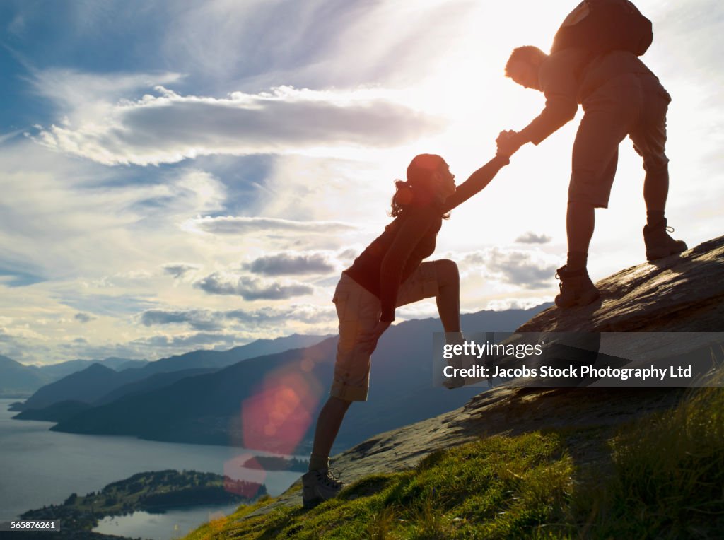 Silhouette of couple climbing hillside near remote lake