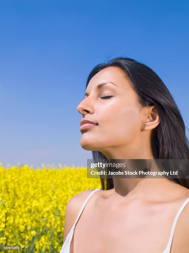 Close up of Indian woman with eyes closed in field of flowers