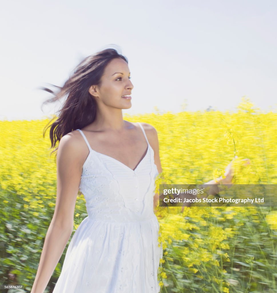 Blurred view of Indian woman walking in field of flowers