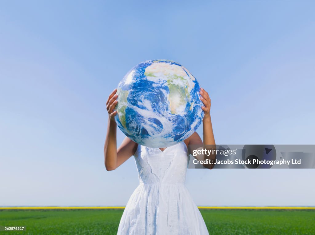 Indian woman holding globe in rural field