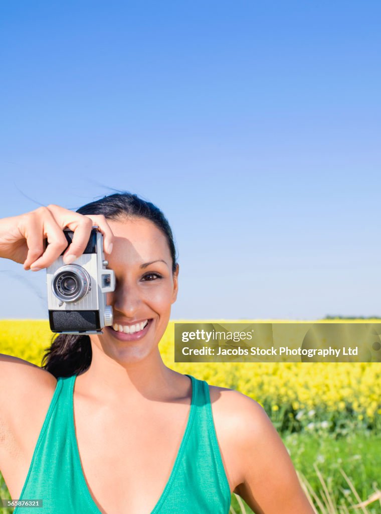 Indian woman photographing in field of flowers