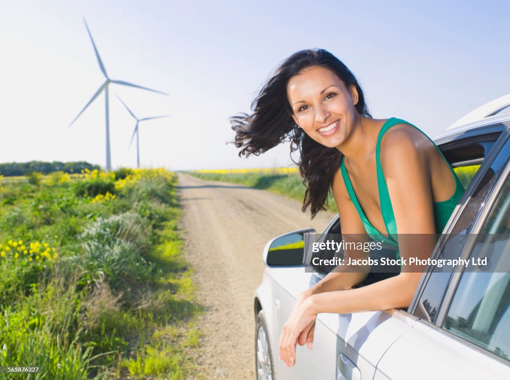 Indian woman driving in car near wind turbines