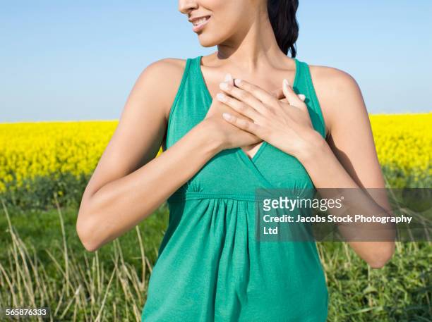 asian woman covering her heart in field of flowers - spalding place stock-fotos und bilder