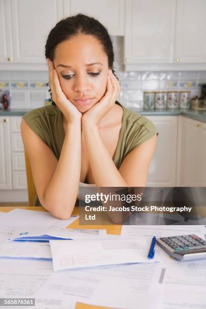 stressed mixed race woman examining bills in kitchen - batalha da grã bretanha imagens e fotografias de stock