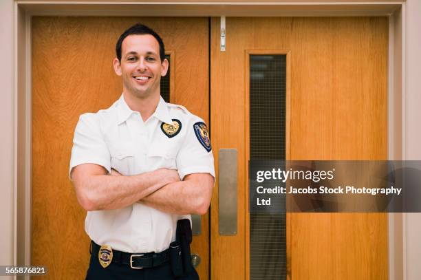 caucasian security guard standing at door - security guard stockfoto's en -beelden
