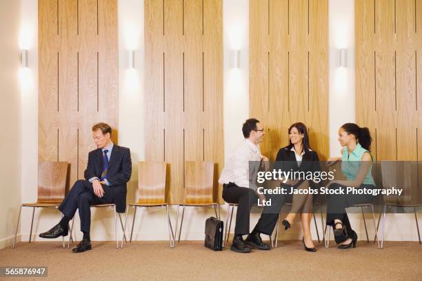 business people ignoring businessman in waiting area - außenseiter stock-fotos und bilder