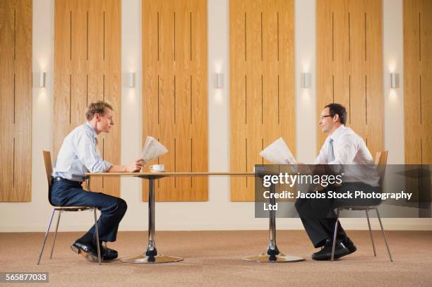 caucasian businessmen reading newspapers at table - side profile face to face stock-fotos und bilder