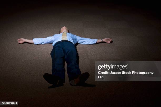lonely caucasian businessman laying on floor in spotlight - fainting fotografías e imágenes de stock