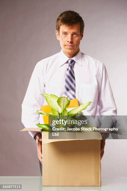caucasian businessman with cardboard box leaving job - rauswerfen stock-fotos und bilder