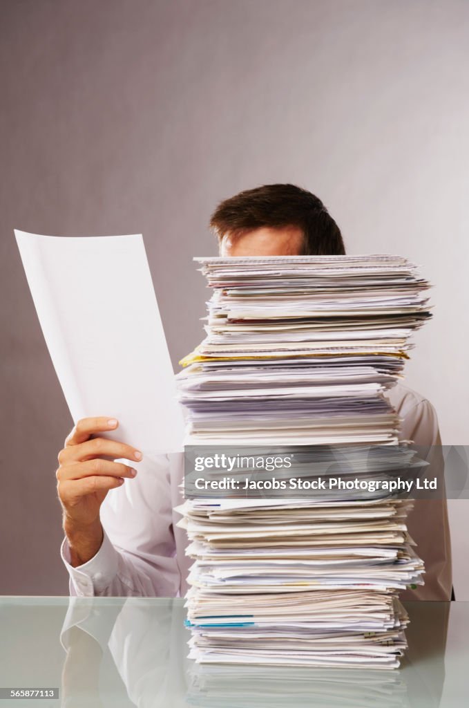 Caucasian businessman reading stack of paperwork