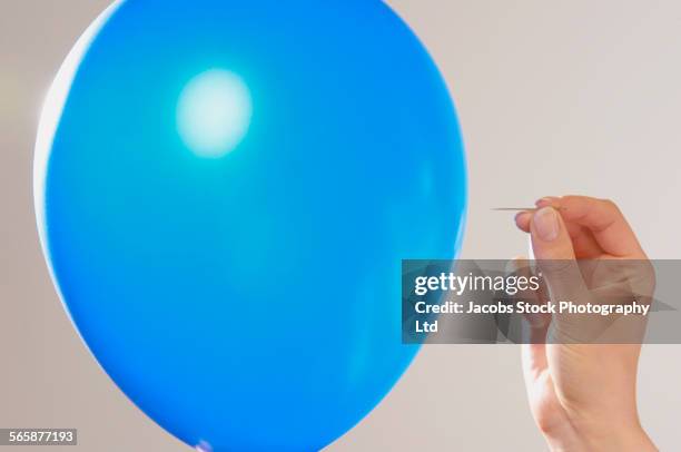 caucasian woman popping blue balloon with pin - aguja fotografías e imágenes de stock