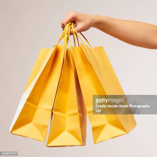 caucasian woman holding yellow shopping bags - shopping bag in hand stockfoto's en -beelden