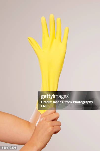 caucasian woman pulling on yellow rubber glove - spülhandschuh stock-fotos und bilder