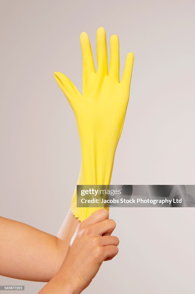 Caucasian woman pulling on yellow rubber glove