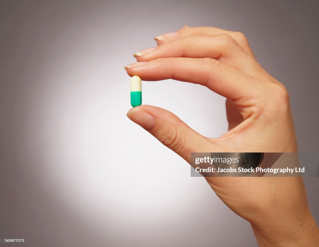 Caucasian woman holding medication pill