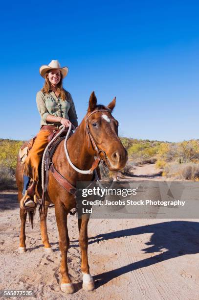 caucasian rancher riding horse on dirt path - horseback riding arizona stock pictures, royalty-free photos & images