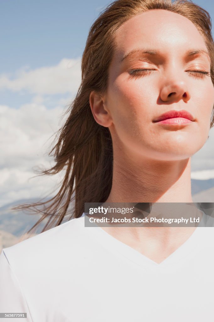 Pacific Islander woman with eyes closed standing in wind