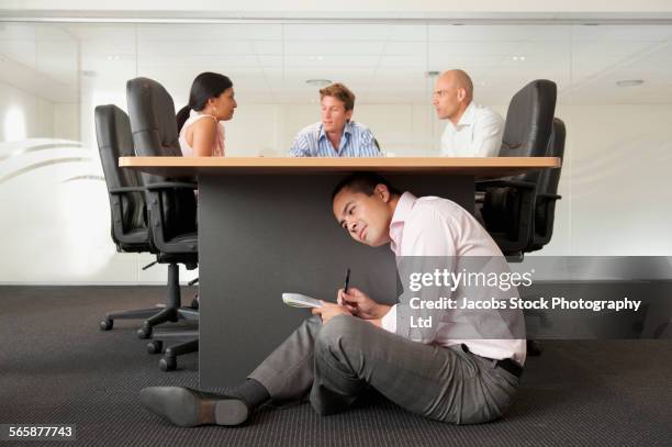 businessman under desk eavesdropping in office meeting - ouvir às escondidas imagens e fotografias de stock