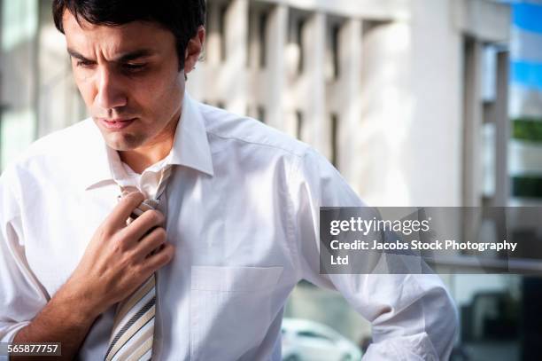 hispanic businessman loosening necktie in office - no tie stock pictures, royalty-free photos & images